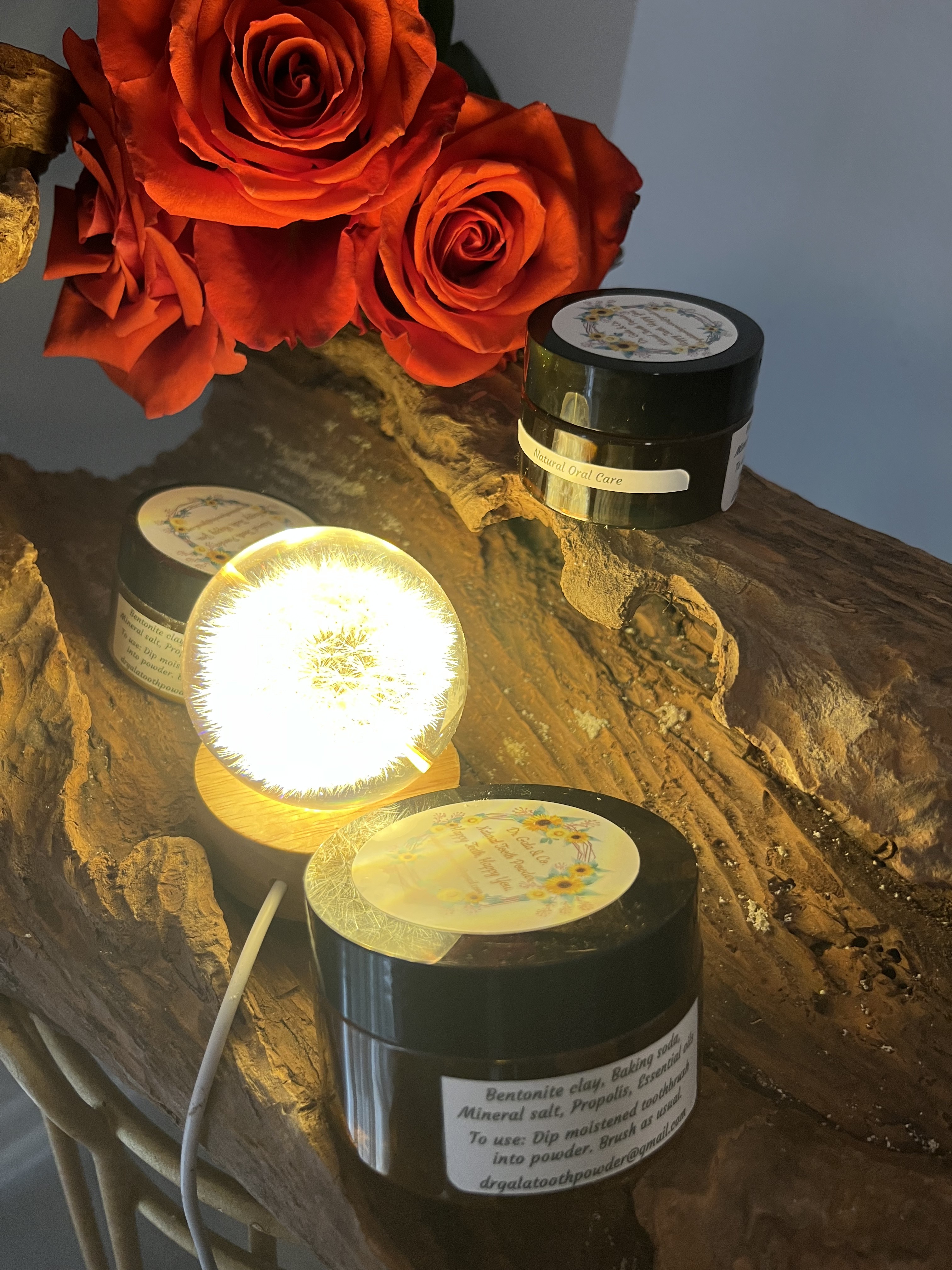 Powder Dent tooth powder jars displayed with roses and warm light